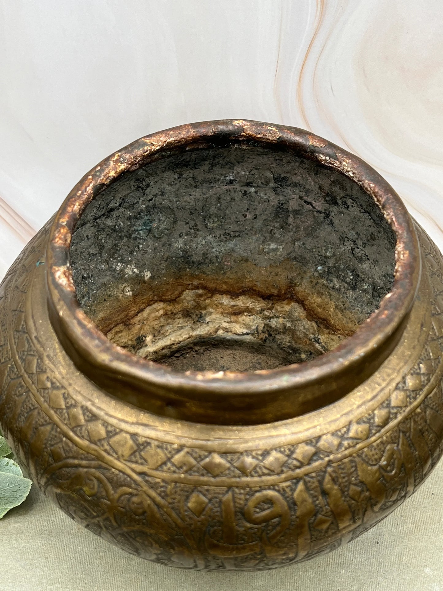 Close-up of a textured bronze pot with intricate designs on a light background