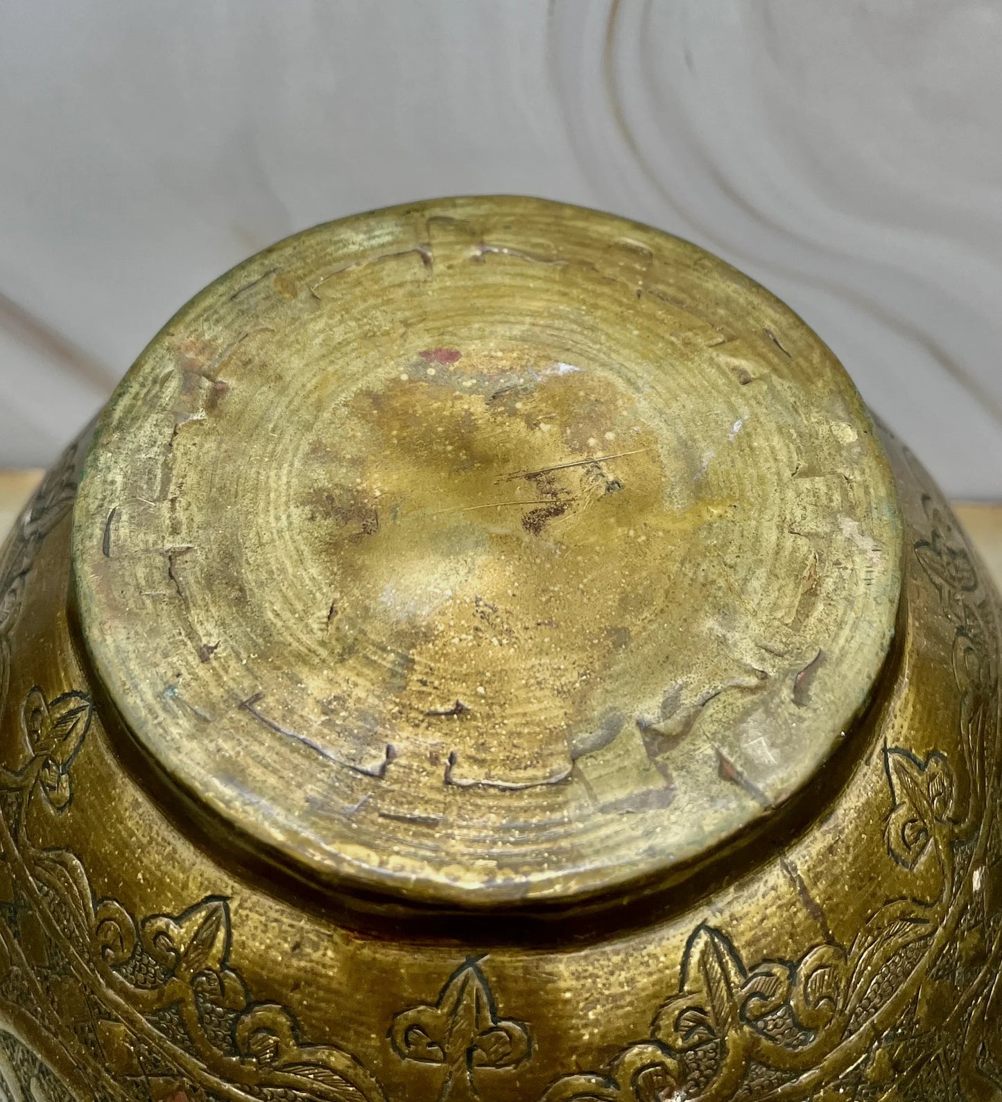 Close-up of a bottom of brass pot with intricate patterns on a white background
