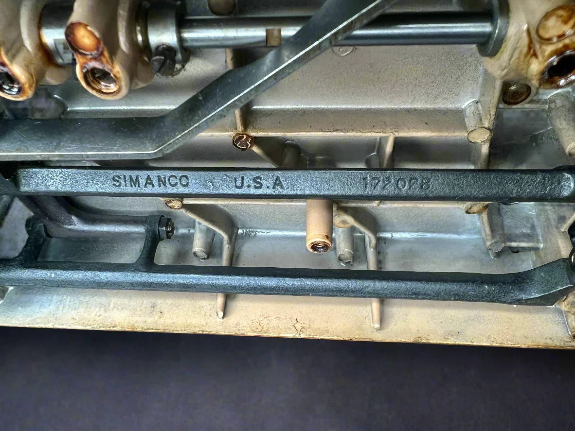 Metallic engine component with 'Simanco U.S.A.' branding on interior mechanics of Singer 403A Slant-O-Matic sewing machine