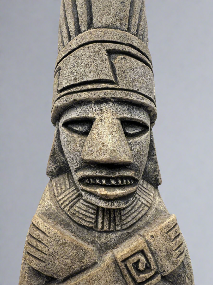 Stone sculpture of a face with intricate patterns on a gray background