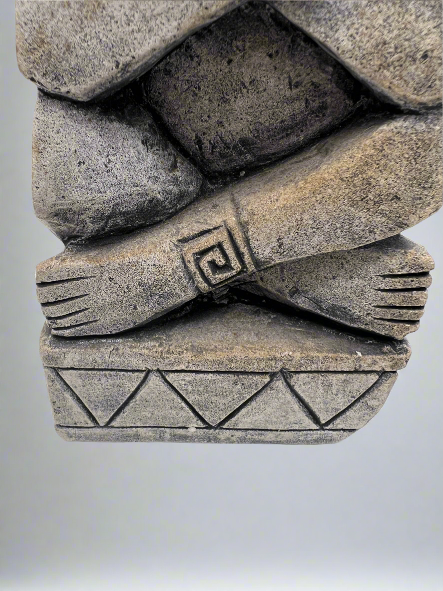 Stone sculpture of a figure with a geometric design on a plain background