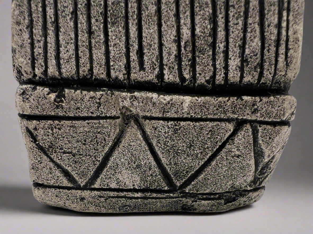 Stone statue with geometric design on a white surface