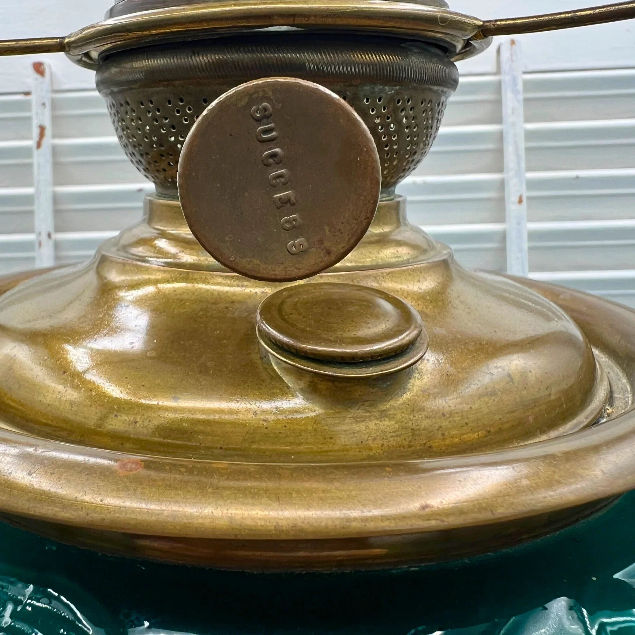 Antique 'Success' converted oil lamp with brass body and emerald green glass, hand-painted lily.