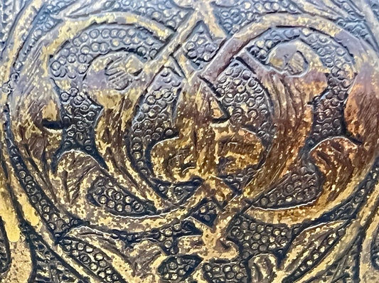 Close-up of intricate gold and black embossed design on a textured surface