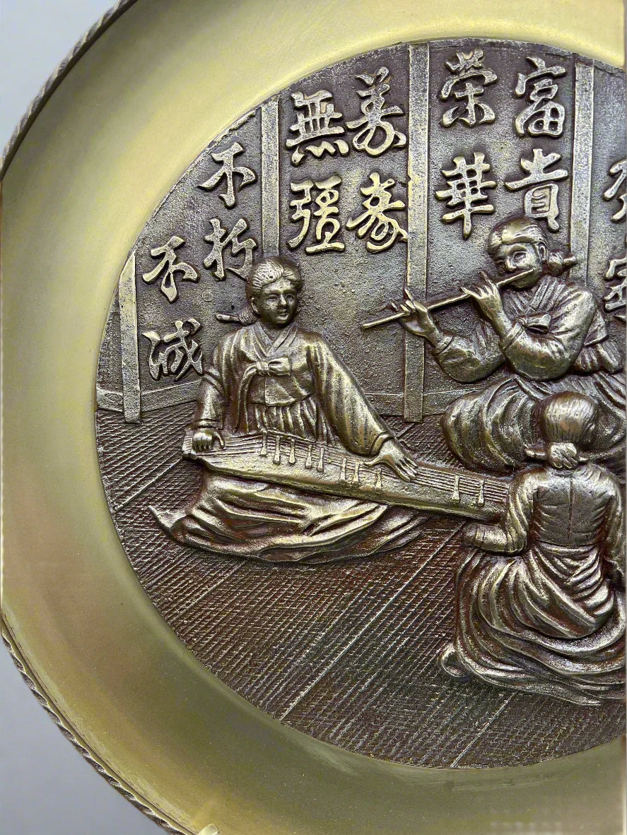 Bronze medallion platter with embossed design of people and text on a white background