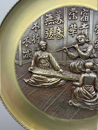 Bronze medallion platter with embossed design of people and text on a white background