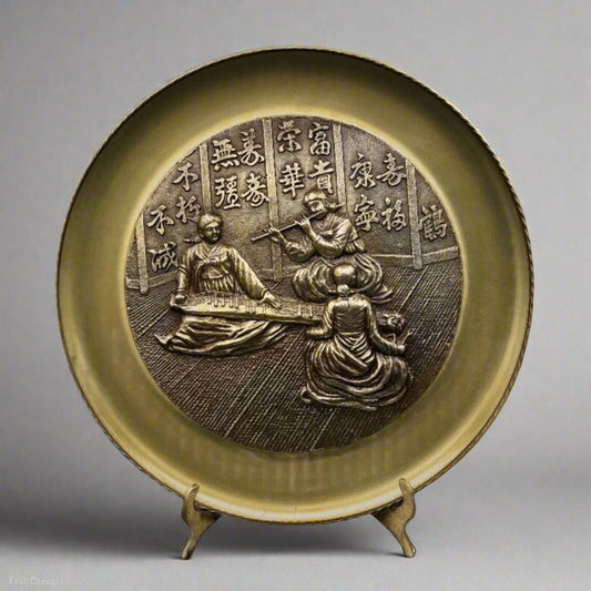 Decorative plate with embossed design on a stand against a gray background