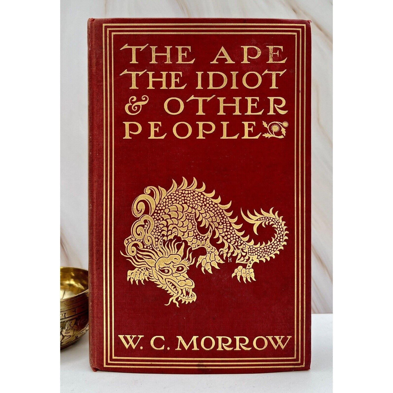 The Ape, The Idiot & Other People by W. C. Morrow, red clothbound first edition cover with gold dragon.
