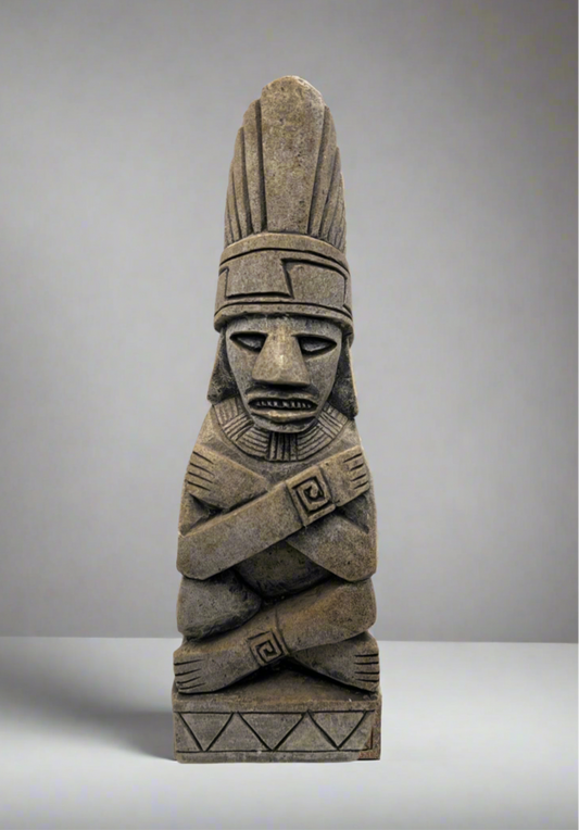 Stone sculpture of a figure with a headdress on a gray background