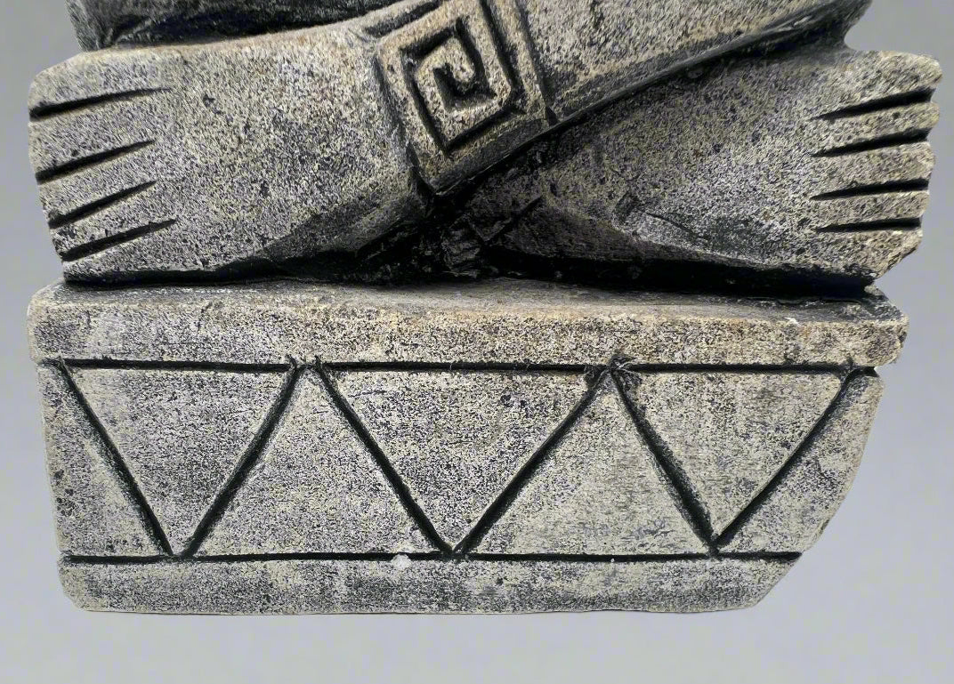 Close-up of a stone sculpture with geometric patterns on a gray background