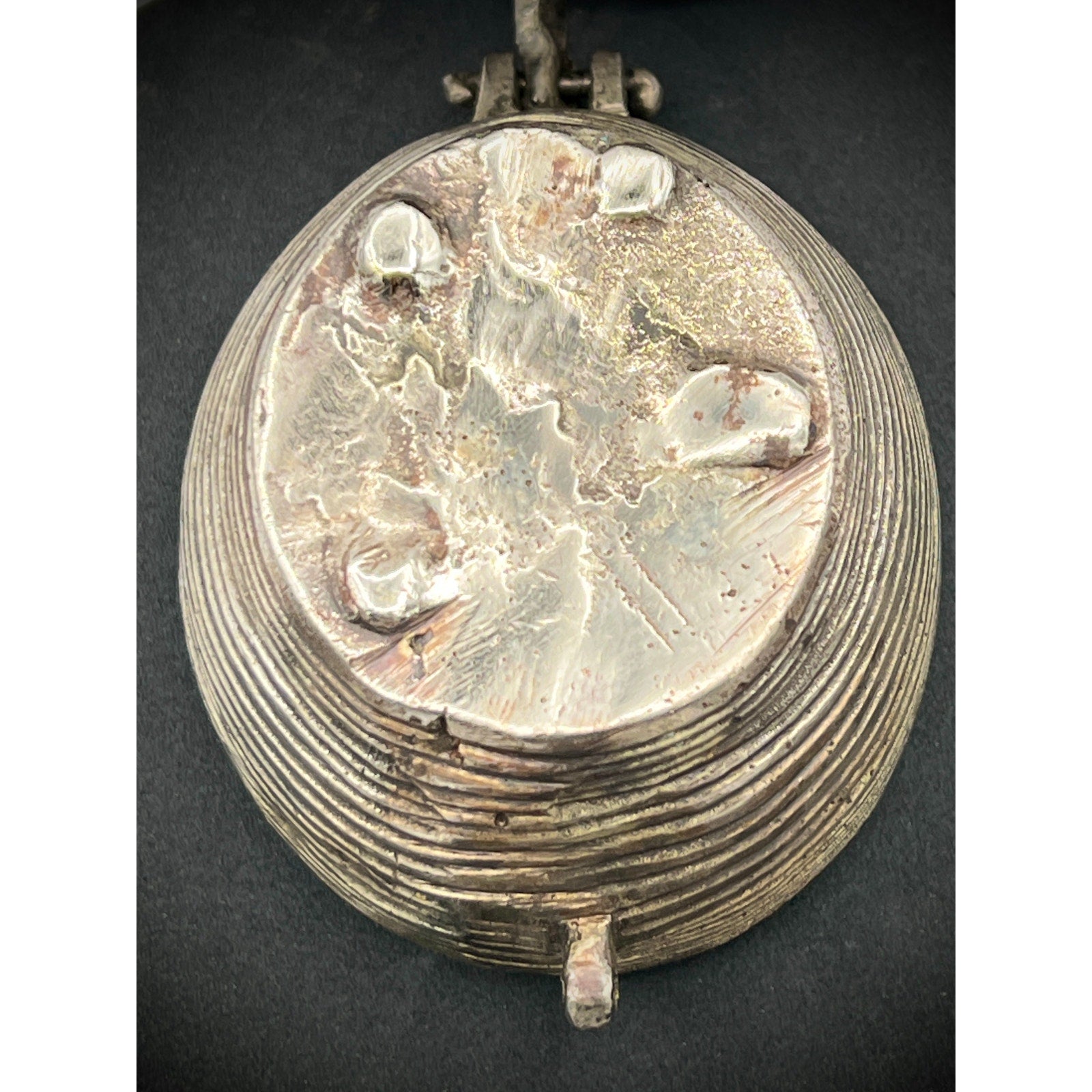 Vintage silver trinket box with engraved design on a dark background