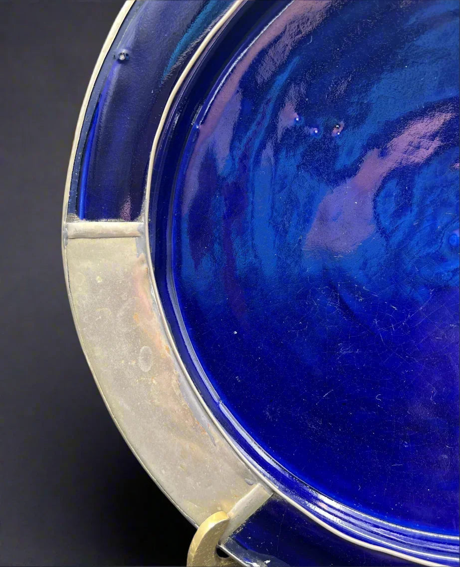 Close-up of a blue glass plate with a silver rim on a white background