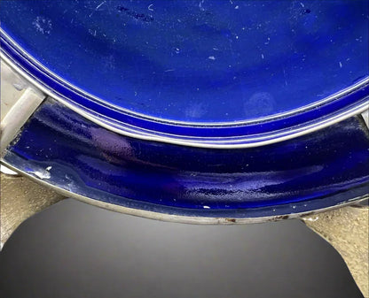 Close-up of a blue ceramic plate with a metallic rim on a white background