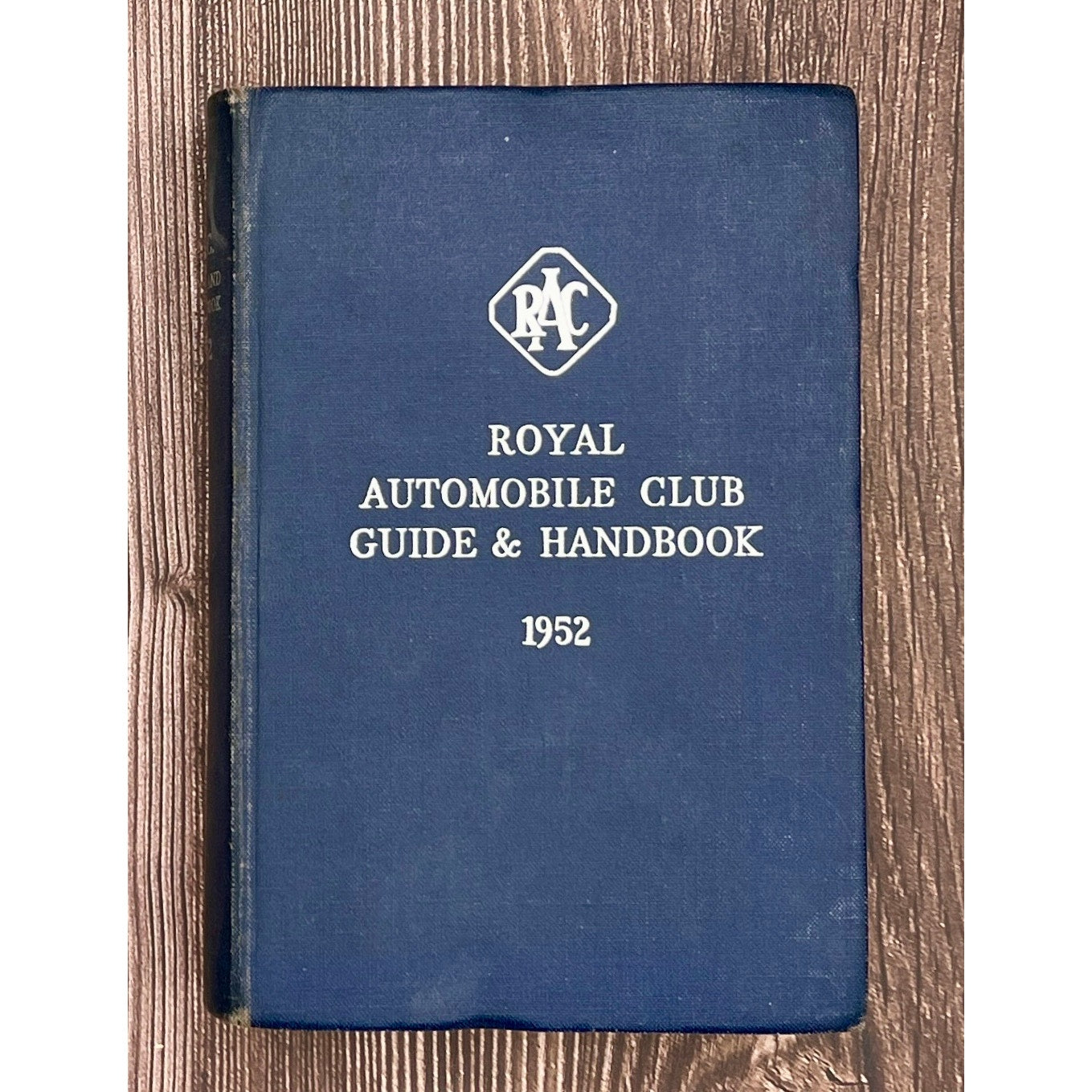 Blue book titled 'Royal Automobile Club Guide & Handbook 1952' on a wooden surface
